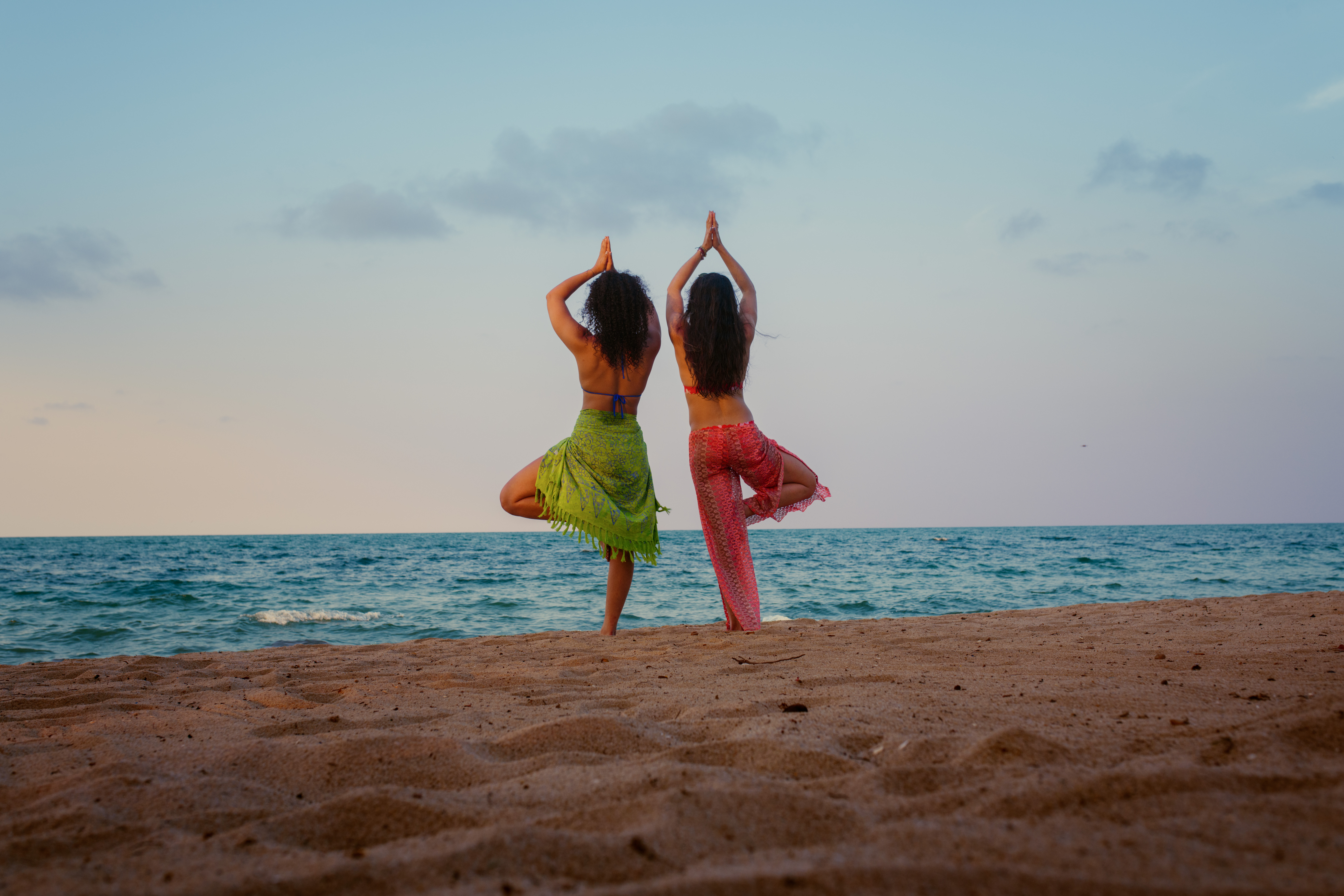 Des femmes pratiquant des postures de yoga sur la plage